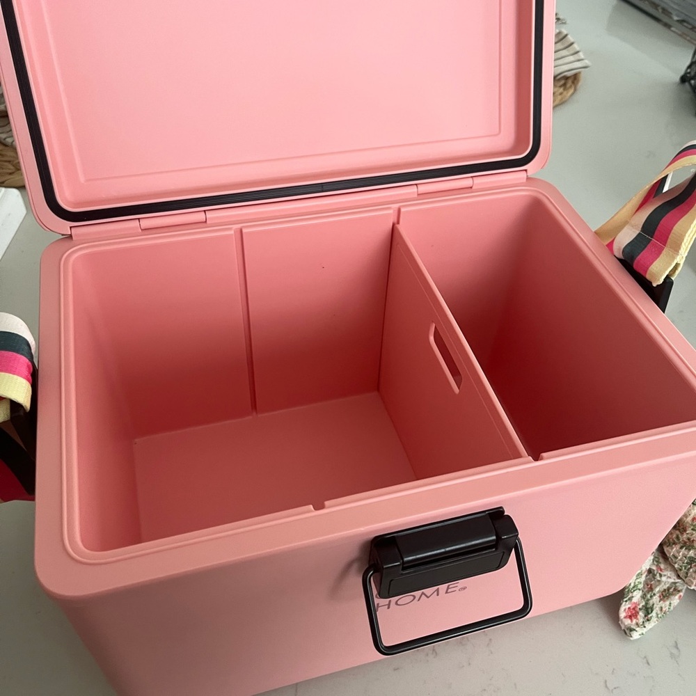 Pink cooler with strap filled with goodies.